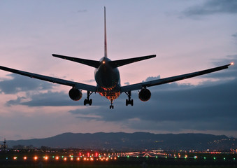 Fototapeta na wymiar 夕焼けの中で滑走路に着陸する旅客機