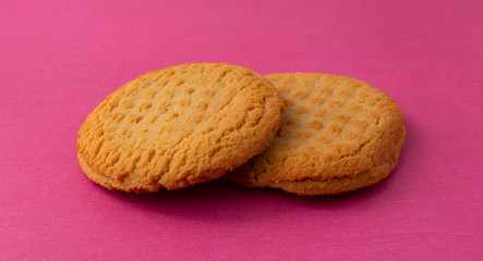 Two peanut butter flavor cookies on a pink background