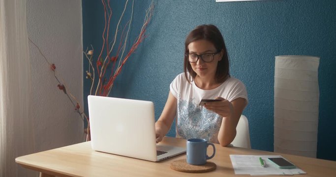 Portrait of a woman buying online or booking hotel with a laptop and credit card in vacations. E-commerce concept