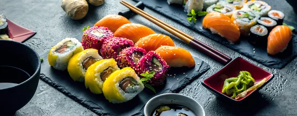 Gordijnen Sushi set sashimi en sushi rolls geserveerd op stenen leisteen © karepa