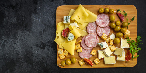 cheese plate (different types of appetizers, sausage, ham, olives, greens and more) menu concept. food background. copy space. Top view