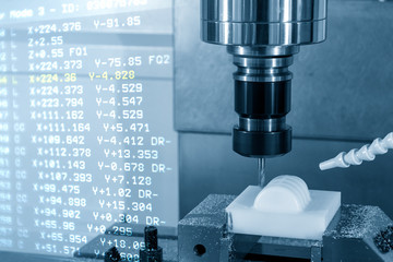 The abstract scene of the G-code data  and the CNC milling machine cutting the resin material parts with solid ball endmill tools. Hi-precision  plastic production process by machining center. © Pixel_B