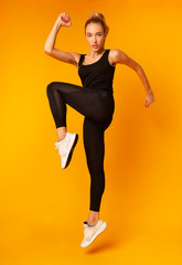 Fitness Woman Jumping While Exercising On Yellow Background, Studio Shot