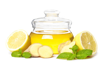 glass jar full of honey and dipper, ginger, lemon and mint isolated on a white background