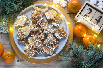 Gingerbread cookies on a concrete tray on a winter background with tangerines, fir branches and a garland.