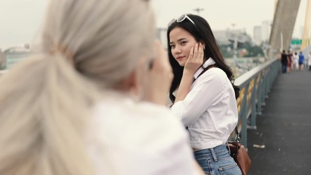 Asian lesbian couples enjoying traveling using film camera taking a photo. Two beautiful young women having fun in vacation time.
