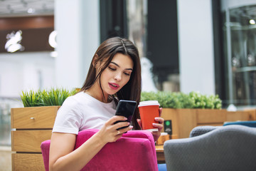 Young adult beautiful brunette girl happy sitting in cafe with coffee and mobile phone