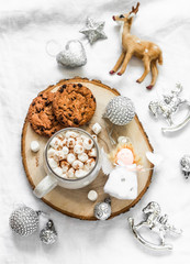 Hot chocolate with marshmallow and cinnamon and chocolate chip cookies surrounded by christmas decorations on a light background, top view. Christmas mood