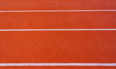 Red running track or resin Emboss Topping with white lines in outdoor sport stadium, side is a field and park. Backgrounds and rubber texture.