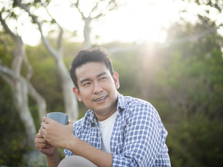 Naklejka na ściany i meble Asian man holding coffee cup with nature outdoor, lifestyle concept.