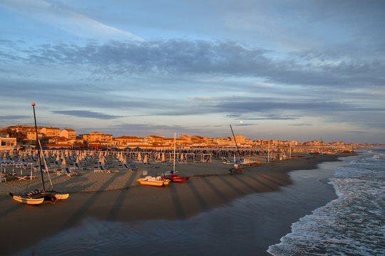 Scenic view of the beach of Lido di Camaiore at sunset with the cityscape in the background, Versilia, Tuscany, Italy