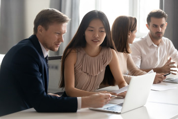 Mentor coach helping Asian female employee with corporate software