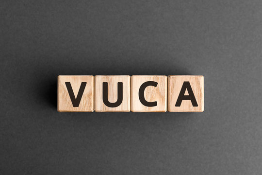 VUCA - acronym from wooden blocks with letters, volatility, uncertainty, complexity and ambiguity VUCA concept,  top view on grey background