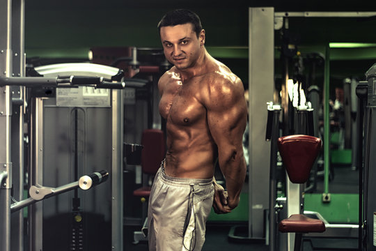muscular bodybuilder doing exercise on bars in the gym. a handsome, sporty, sexy guy with a abs training in the gym. fitness, bodybuilding, nutrition, healthy lifestyle