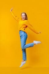 Pretty girl jumping in air and laughing on orange background