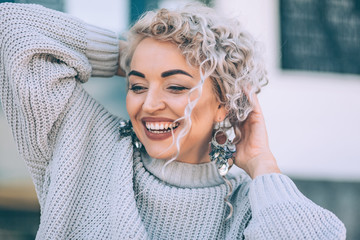 Plus size model with blond curly hair in knitted sweater and silver earrings outdoor