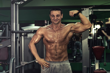 Fototapeta na wymiar muscular bodybuilder doing exercise on bars in the gym. a handsome, sporty, sexy guy with a abs training in the gym. fitness, bodybuilding, nutrition, healthy lifestyle