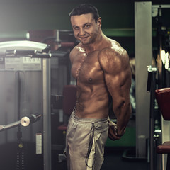 muscular bodybuilder doing exercise on bars in the gym. a handsome, sporty, sexy guy with a abs training in the gym. fitness, bodybuilding, nutrition, healthy lifestyle