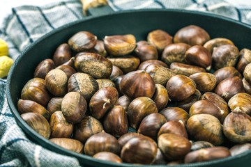 Roasted chestnuts served in chestnut pan on an old table