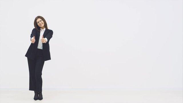 Full length attractive smiling businesswoman in suit standing, giving her thumbs up, smiling joyfully, posing.