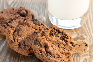 Fototapeta premium Tasty chocolate chip cookies and a glass of milk on a wooden table