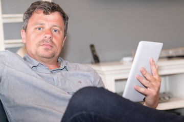 Handsome man at home living room with tablet