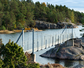 walking bridge between two islands Sweden at the Stend&ouml;rren natural reserv Green trees an see in the background rocks under the bridge