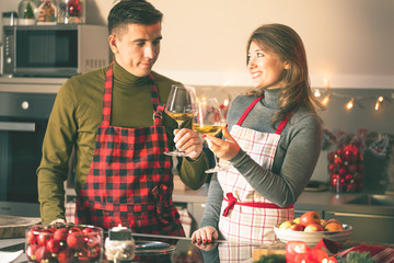 Couple celebrating Christmas in the kitchen and drink wine
