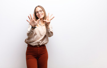 young pretty woman smiling and looking friendly, showing number nine or ninth with hand forward,...