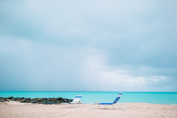 Fototapeta na wymiar White lounge chairs on a beautiful tropical beach at Maldives