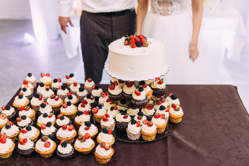 Wedding cake and cupcakes with berries. Cream cakes.