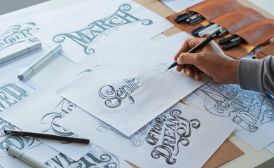 Typography Calligraphy artist designer drawing sketch writes letting spelled pen brush ink paper table artwork.Workplace design studio. - obrazy, fototapety, plakaty