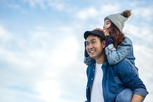 Piggy back Asian couple with blue sky and cloud, love concept.