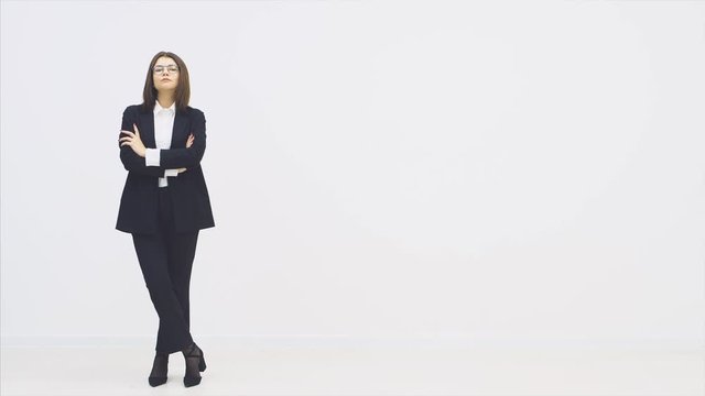 Full length attractive businesswoman in suit standing with arms folded, looking seriously at the camera, posing.
