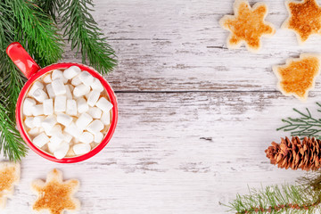 Red cup with hot cocoa and marshmallows, toasted shaped bread slices on wooden table in Christmas New Year season decorations with fir tree branches. Cozy winter breakfast concept. Copy space.