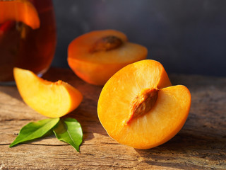 Golden juicy peach cut in half on rustic wooden table with sunlight.