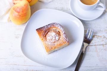 Mannik (Semolina pie) with pear and canella. In the background is a cup of coffee and fresh pears. Traditional Russian cuisine. Close-up, selective focus.