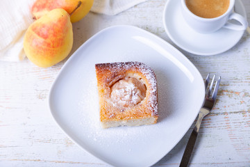 Mannik (Semolina pie) with pear and canella. In the background is a cup of coffee and fresh pears. Traditional Russian cuisine. Close-up, selective focus.