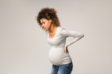 Pregnant woman with contractions, touching her back
