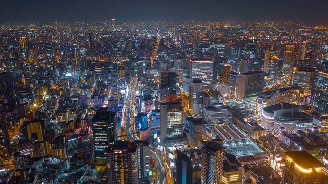 Aerial night hyper lapse over Osaka city with Umeda(Osaka) train station and many skyscraper building and vehicles.