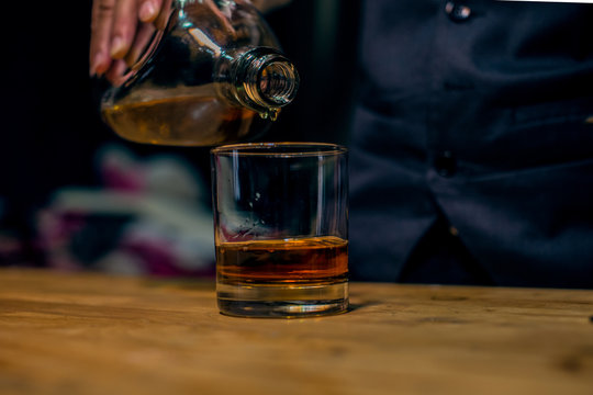 Glass Of Whiskey And Ice On Wooden Table