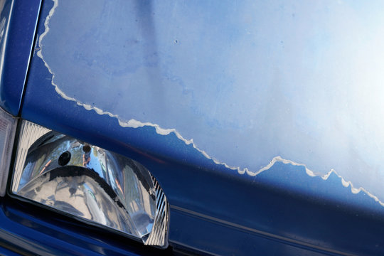 front hood blue car with damaged and peeled paint protective lacquer in closeup