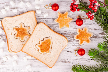 Slices of toast bread with a toasted cut out shaped like a fir-tree and snowflake with white...