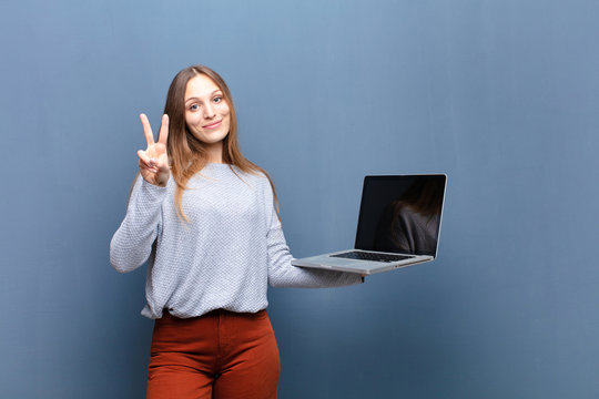 Young Pretty Woman With A Laptop Against Blue Wall With A Copy Space