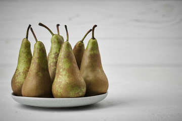 fresh pear in a white plate. white wood background