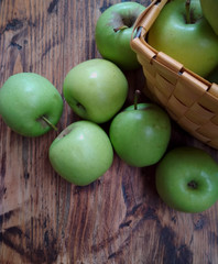 green apples in  basket on vintage wooden table