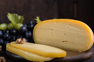 Dutch hard cheese Maasdam or Emmentaler, with honey fruit and grape