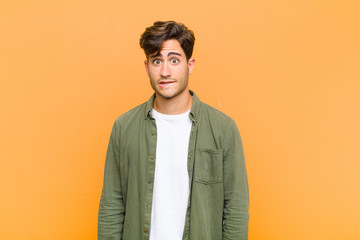 young handsome man feeling clueless, confused and uncertain about which option to pick, trying to...