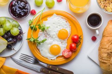Homemade breakfast with sunny side up fried egg croissant toast coffee fruits vegetable and orange juice in top view with copy space. Delicious homemade american breakfast concept for background. Amer