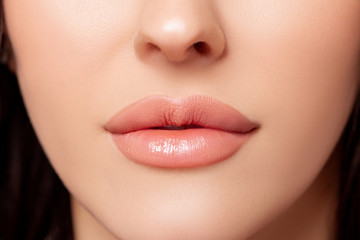 Beauty Fashion woman lips with natural Makeup. shine lipstick. Beauty girl face close up. Closeup mouth Nude Colors lacquered. Sexy lips, Make up. Over peach background. big lips  